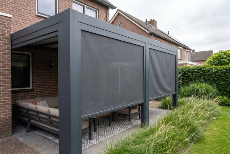 Donkergrijze zip screens half neergelaten aan de zijkanten van een aluminium veranda