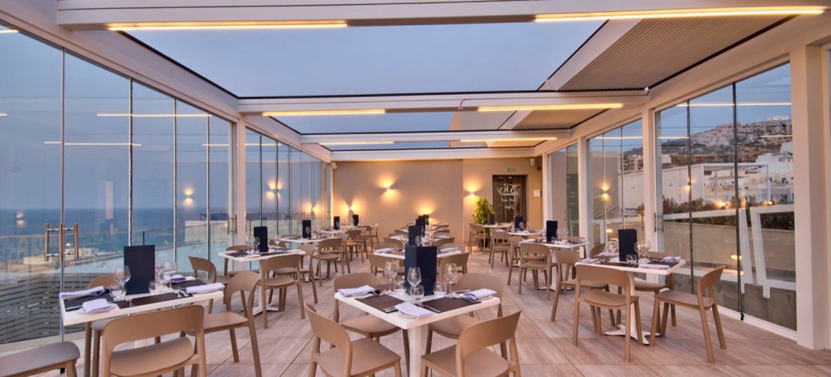 Overkapping met geopend daksysteem en dimbare LED-verlichting in de avond